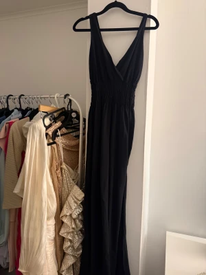 Svart långklänning med v-ringning - Svart långklänning med djup v-ringning och smockad midja. 