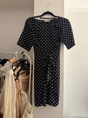 Svart prickig klänning från Pieces - Supersöt svart kortklänning från Pieces med vita prickar och knyt i midjan. 