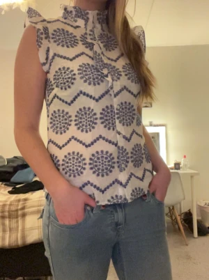 Blå, vit kortärmad topp - Säljer denna fina blå, vita toppen från Holly & White. Toppen har volanger längst axlarna och kragen samt lite volanger längst knapparna.💕🫶