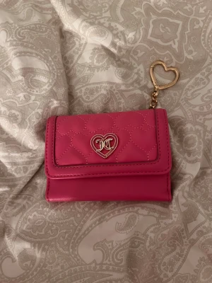 Rosa plånbok från Juicy Couture - Superfin rosa plånbok från Juicy Couture med quiltad framsida och hjärtmönster. Den är köpt i Kanada för 1 år sen har bara kommit till användning 2-3 gånger. Den ger en lyxig känsla av Juicy Couture💕pris kan diskuteras!