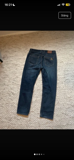 Burberry mörkblå jeans straight fit - Snygga mörkblå jeans från Burberry med klassisk straight fit och broderad Burberry-logga i guld på bakfickan. Jeansen har fem fickor, bälteshällor och detaljerade sömmar med färginslag. Perfekt för dig som gillar stilrena designer. Nypris 7600kr   Midja 45cm längd 100cm skick 9/10