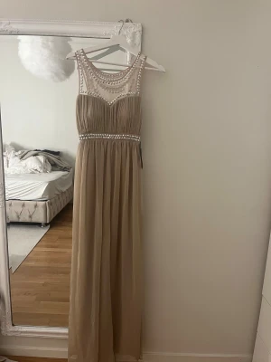 Champagnefärgad långklänning med pärldetaljer - Super fin klänning. Helt ny med prislapp på.
