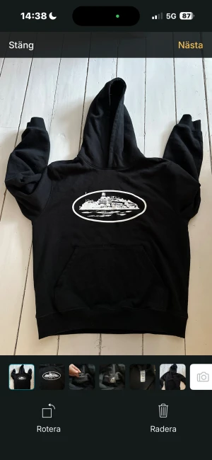 Svart hoodie från Corteiz med tryck - Svart hoodie från Corteiz i storlek medium med stort vitt tryck av en byggnad på bröstet. Tröjan har huva, magficka och ribbade muddar vid ärmslut och nederkant. Materialet är mjuk bomull och polyester, perfekt för dig som gillar streetwear och grafiska prints.