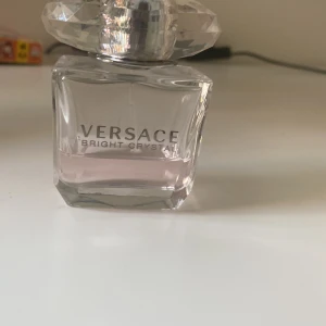 Versace Bright Crystal Parfym - Elegant parfymflaska från Versace med en ljusrosa doftvätska. Flaskan har en lyxig, kristalliknande kork och en stilren design. Perfekt för den som älskar en fräsch och blommig doft. 30 ml och köpt för ca femhundra från kicks❤️