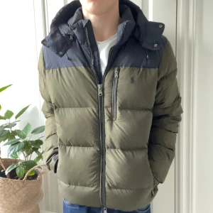 Ralph Lauren dun jacka  - Ralph Lauren dun jacka i storlek L. Modellen är 180 cm 75 kg. Inga som helst defekter och jackan är i nyskick! Men stor på modellen, rekommenderas för 185-195. Man kan dra åt i midjan beroende på hur man vill den ska sitta och har även många fickor med dragkedja. Perfekta jackan för nu i vintern! Väldigt fin jacka med nypris omkring 5000 kr, mitt pris 2500 🏆 SJÄLVKLART ÄKTA ✅
