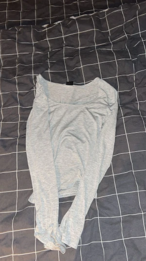 Ljusgrå långärmad topp med slits i ärmen  - Säljer en enkel och stilren ljusgrå långärmad topp med rundad hals. Toppen är i mjukt material och har en normal passform som är skön att bära. Perfekt att matcha med jeans eller kjol för en chill look.