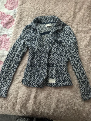 Mönstrad stickad jacka Odd Molly - Säljer en blåvit stickad cardigan jacka från Odd Molly med snyggt geometriskt mönster. Jackan har krage, lång ärm och är i mjukt material som känns skönt mot huden. Perfekt för dig som gillar unika detaljer och vill sticka ut lite extra.