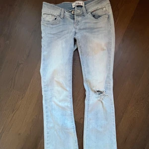 Ljusblå jeans från G-Rise med slitning - Snygga ljusblå jeans från G-Rise med klassisk femficksdesign och cool slitning på ena benet. Jeansen har raka ben, silverfärgade nitar och ljusa sömmar med en touch av rosa. Perfekt för dig som gillar en avslappnad streetstil. Kom med prisförslag då jag inte är säker på om ja vill sälja. Modellen finns inte kvar och är därför svåra att få tag på!! Nya kostade 1500 så säljer inte under de!