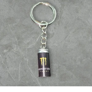 Nyckelring med Monster Energy design - Cool nyckelring med en liten Monster Energy burk som hänge. Perfekt för att ge dina nycklar en unik stil. Burken är i svart med den ikoniska gröna loggan. En rolig accessoar för alla Monster Energy fans!