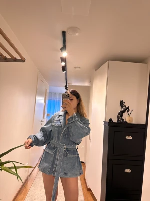 Oversized jeansjacka med bälte - Säljer en oversized jeansjacka i klassisk blå denim med stora fickor och bälte i midjan. Jackan har långa ärmar, bred krage och cool utility-vibe. Perfekt för dig som gillar streetstyle och vill ha en statement piece i garderoben.