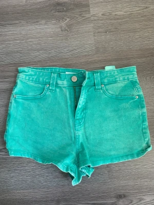 Turkosa denimshorts Lucy Denim - Snygga turkosa shorts från Lucy Denim i klassisk femficksmodell. De har hög midja, knapp och dragkedja framtill samt bälteshällor. Materialet är mjuk bomullsdenim som ger en chill vibe. Perfekta för att sticka ut med färg i sommar.