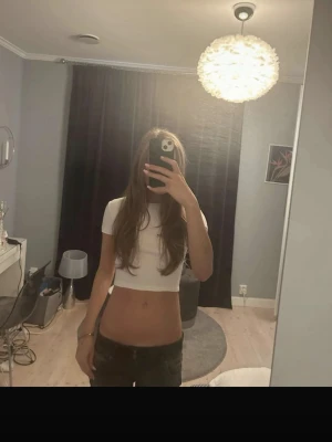 Vit croppad topp med kort ärm  - Säljer en enkel och stilren vit croppad topp med korta ärmar. Toppen har en tight passform och är perfekt till höga jeans eller kjol. Materialet känns mjukt och stretchigt, troligtvis bomull eller en bomullsblandning.