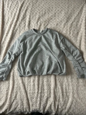 Grå sweatshirt  - Säljer en stilren grå sweatshirt i storlek S. Tröjan har rund halsringning, långa ärmar och är gjord i mjukt material som känns skönt mot huden. Perfekt för en avslappnad och enkel look.