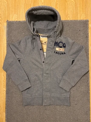 Vintage Hollister Cardigan Med Knappar & Zip - Säljer denna mycket snygga och unika Hollister cardigan med både zip och knappar! Små slitningar ska förekomma | Storlek S | Längd ≈ 65-66cm Bredd armhåla - armhåla 53-54cm | Hör gärna av vid funderingar!