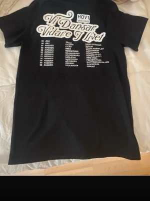 Svart Hov1 t-shirt med tryck - Säljer denna svarta t-shirt från Hov1 konserten. T-shirten har hov1 loggan broderad på bröstet och stort turnétryck på ryggen. Klassisk passform och rund hals. Perfekt för dig som gillar hov1 och vill ha en stilren merch-tröja. Inga fläckar eller hål och har använts 2 gånger. Pris kan diskuteras!💞