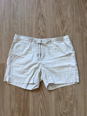 Beiga shorts med dragkedja och snörning från H&M, storlek 40 - Beiga shorts i bomull med snörning i midjan och fickor både fram och bak. Perfekta för vår/sommar! Sparsamt använda!