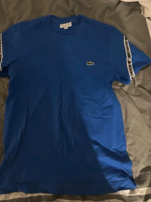 Blå Lacoste t-shirt med logoband - T shirt från lacoste! Storlek S!