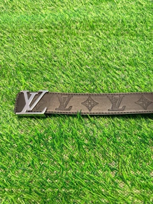 Louise Vuitton svart skärp med monogram - Snyggt svart skärp från Louise Vuitton med klassiskt L.V-monogram och silverfärgat L.V spänne. Skärpet är gjort i skinn och har präglade loggor längs hela bandet. Perfekt accessoar för att lyfta din outfit.