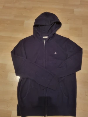 Oanvänd stickad hoodie från Gant - Mörkblå stickad ull hoodie från Gant med dragkedja, träjqn ör helt oanvänd, söljer pga av att den är för stor (176=S)🙌 ny pris, 1200kr, säkjer för 660 då jag vill ha den såld snabbt. Går med på o sänka pris för snabb affär🙏🏼