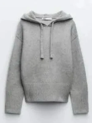 Grå stickad hoodie  - Mysig grå stickad hoodie med huva och dragsko. Tröjan har ribbade muddar vid ärmslut och nederkant samt en avslappnad passform. Perfekt för en chill och stilren look.
