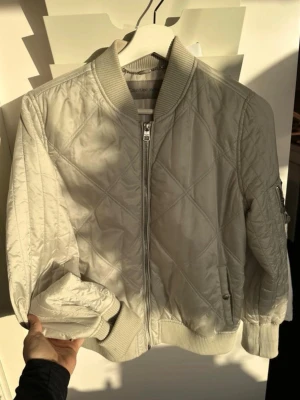 bomberjacka Calvin Klein - Snygg bomberjacka från Calvin Klein med quiltat mönster och ribbade muddar. Jackan har dragkedja framtill, fickor på sidorna och en ärmficka. Perfekt för dig som vill ha en stilren och trendig look.