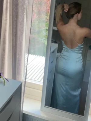 Ljusblå långklänning med slits - Säljer en elegant ljusblå långklänning i satinliknande material. Klänningen har tunna axelband, öppen rygg och en hög slits framtill som ger en snygg touch. Perfekt för dig som vill sticka ut på nästa bal eller fest. Använd vid 1 tillfäll, pris går att diskutera