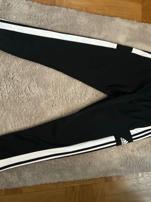 Svarta Adidas mjukisbyxor med vita ränder - Säljer ett par adidas byxor som inte har blivit mycket använda. Det är storlek L och dom är i jätte fint skick nästan helt nya. 