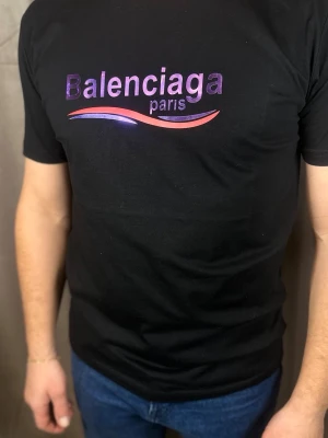 Svart  Paris t-shirt - Snygg svart t-shirt  med glansigt lila och rött tryck på bröstet där det står '' och en vågig detalj under texten. Klassisk passform och rund hals. Perfekt för dig som vill ha en statement tee från ett lyxigt märke.