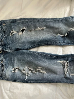 Blå slitna jeans med hål - skiiitsnygga lågmidjade bootcut jeans med hål. använda mycket men jättefint skick (se bild 2 där de är lite slitna). skriv för mått och fler bilder! pris kan diskuteras! 