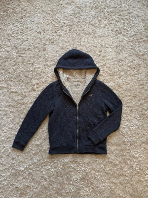 Blå fodrad zip hoodie från hollister - Snygg hoodie från hollister, den är fodrad o varm. Använd men i gott skick, storlek S!