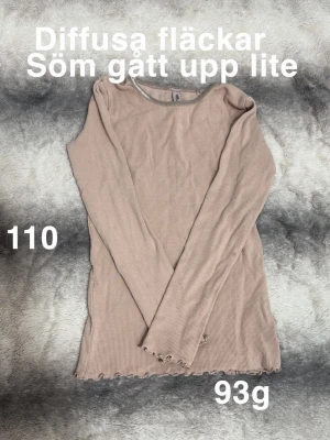 Rosa ribbad långärmad topp - Trendig rosa långärmad topp med ribbad struktur och vågig kant nertill. Perfekt basplagg med enkel rund halsringning och smal passform. Passar till allt och är superenkel att styla.🌸 Diffusa fläckar. Sömnen vid kantbandet i nacken har öppnat sig lite. Storlek 110 