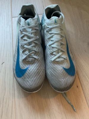 Nike mecurial vapor 16 elite blå fotbollskor - Säljer ett par nike mecurial elite fotbollsskor med blå swoosh och snygga detaljer på sidan. Skorna har låg profil, snörning och är tillverkade i ett lätt syntetmaterial som ger bra bollkontroll och grepp på planen. Perfekta för dig som vill ha stilrena och snabba skor på matchen.