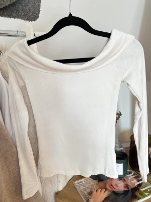 Vit offshoulder topp Reserved - Säljer en vit offshoulder topp från Reserved. Toppen har lång ärm och en bred, nedvikt krage som ger en snygg offshoulder-look. Perfekt att styla med jeans eller kjol för en trendig vibe.
