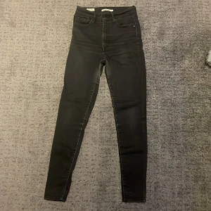 Levi's Mile High Super Skinny jeans svart - Svarta Levi's Mile High Super Skinny jeans med hög midja och supertight passform. Klassisk femficksmodell med Levi's-detaljer på bakfickorna. Snyggt stretchigt denimtyg som sitter som en andra hud och framhäver siluetten.