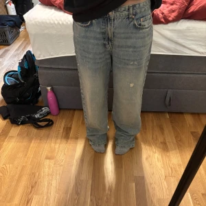 Blåa baggy jeans från Gina tricot strl 36 - Säljer ett par ljusblå jeans från Gina.  Jeansen är i bomull och har slitna detaljer framtill för en cool vintagekänsla. Dom är högmidjade men jag har som låga och baggy istället. Jag har oftast 32 men blir baggy eftersom dom är i 36. Slitna nertill vid fötterna.