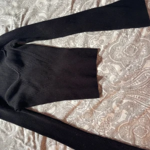 Svart ribbad stickad tröja H&M - Svart, ribbad och figurnära stickad tröja från H&M. Tröjan har lång ärm och markerade sömmar över bysten som ger en snygg form. Perfekt till höst och vinter, enkel att matcha med jeans eller kjol.