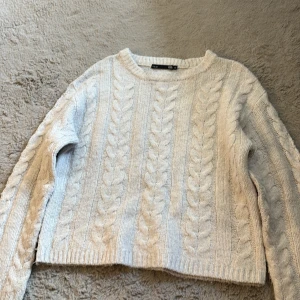 Vit stickad tröja från lager 157 - Säljer en vit stickad tröja från lager 157 i storlek XS. Tröjan har ett snyggt flätmönster framtill och på ärmarna, rund hals och ribbade muddar. Perfekt för dig som gillar mysiga och stilrena plagg med lite chunky känsla.
