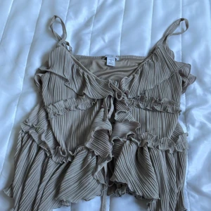 Grön volangtop från Amisu - Använd nån gång bara. Supersöt grön linnetopp från Amisu med tunna axelband, plisserat tyg och volangdetaljer över hela toppen. Toppen har knyt framtill och en flowy, luftig känsla som passar perfekt till varma dagar. Ger en romantisk och trendig vibe. St m men passar typ xs-m