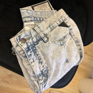 Jeansshorts från Monki - Snygga ljusblå acid wash jeansshorts från Monki med hög midja och råa, fransiga kanter. Med knapp och dragkedja framtill.
