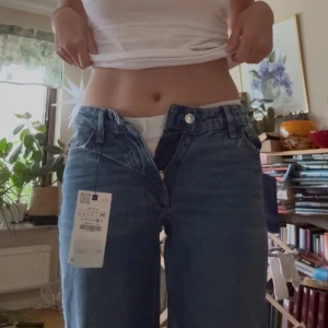 nya zara jeans - Säljer ett par klassiska blå jeans med rak passform och låg midja. Jeansen har fem fickor, bälteshällor och stängs med dragkedja och knapp. Materialet är robust denim i bomull och modellen är loose och straight. Perfekta för en avslappnad stil.