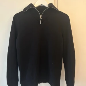Svart half zip-tröja Jack & Jones - Svart långärmad tröja från Jack & Jones Core med ribbad krage och snygg half zip-dragkedja. Tröjan är i ett mjukt material och har en stilren look som passar perfekt till jeans eller chinos. Storlek XS men sitter som S. Säljer då jag inte nästan aldrig använt den.
