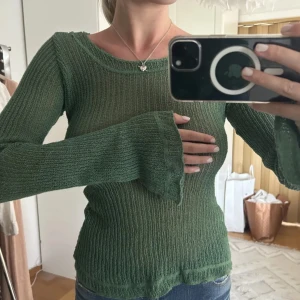 Grön ribbad stickad tröja - Säljer en tunnstickad grön tröja med ribbat mönster och långärmad modell. Tröjan har lätt utsvängda ärmslut och en något transparent känsla, perfekt för lager-på-lager. Snygg till både jeans och kjol.