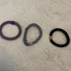 Tre knekkie armband - Tre knekkie armband i olika färger: lila med glittrande pärldetalj, silvergrått och svart med guld🌈. Perfekta accessoarer för att ge din outfit en unik touch.✨15 styck!