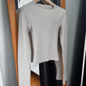 Beige ribbad långärmad topp A-DSGN - Säljer en stilren beige långärmad topp från A-DSGN i storlek XXS. Toppen är ribbad och har en rak, enkel passform med rund halsringning.