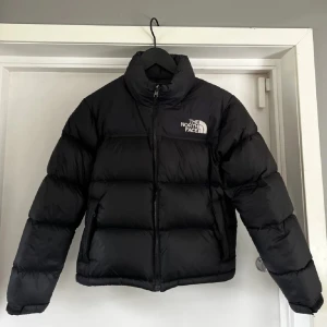 Svart pufferjacka från The North Face - Säljer en svart pufferjacka från The North Face Nästan helt oanvänd endast en liten defekt på ena armen som knappt syns. Perfekt till vintern. Storlek xxs-s