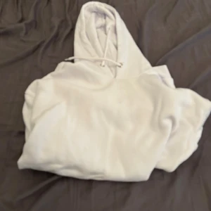 Vit hoodie med ficka och luva från pier one. - En stilren vit hoodie med klassisk känguruficka och dragsko i huvan. Tröjan har långa ärmar och är tillverkad i mjukt material som känns skönt mot huden. Perfekt för en avslappnad look och enkel att matcha med jeans eller joggers. Från pier one.