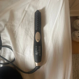 OBH Nordica Björn Axén Tools Curl & Straight Go - OBH Nordica Björn Axén Tools Curl & Straight Go är en mångsidig stylingborste med justerbar temperatur (130-230°C) och jonfunktion för glansigt hår. Produkten är i gott skick utan synliga defekter eller slitage. Perfekt för både lockar och rakt hår.