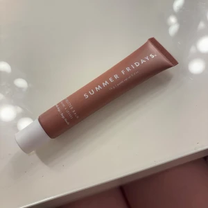 Summer Fridays Butter Balm läppbalsam - Summer Fridays Butter Balm är ett veganskt läppbalsam i en snygg beige-rosa tub med vit kork. Perfekt för att återfukta och mjukgöra läpparna, med en smidig applikator och stilren design. Den är trendig.  Och inte använd