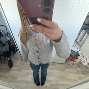 Grå stickad kofta med snörning - Superfin grå stickad kofta med breda band som snörning framtill. Koftan har långärmade ärmar och en mysig, lite loose passform. Perfekt att slänga på sig när det är kyligt ute. Aldrig använd, går absolut att diskutera pris💕