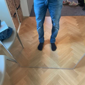 Jack & Jones jeans blå 29/30 - Snygga slim fit jeans från Jack & Jones i modellen slim/glenn i klassisk blå tvätt. Modellen har smal passform, fem fickor och normal midja. Jeansen är tillverkade i mjukt denimtyg och passar perfekt till en avslappnad stil.